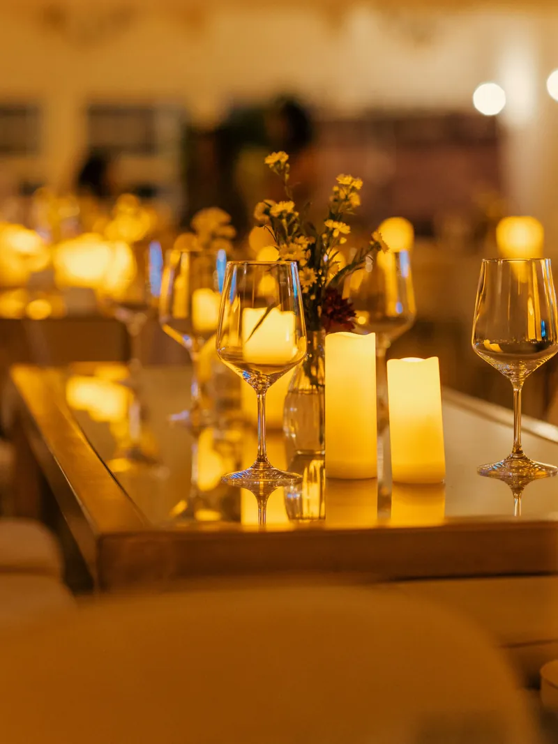 Copas de vino y velas encendidas sobre una mesa de vidrio