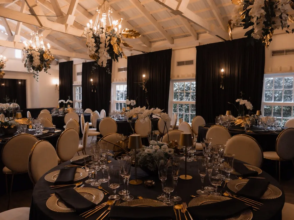 El salón montado en negro y dorado para una cena de empresa, con mesas redondas y candelabros