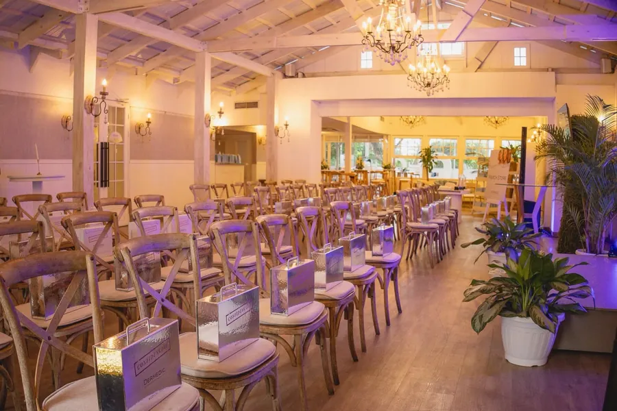 El salón montado para una presentación de empresa, con filas de sillas de madera y luz morada